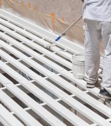 Painter Rolling White Paint Onto Top of Patio Cover