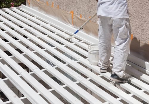 Painter Rolling White Paint Onto Top of Patio Cover